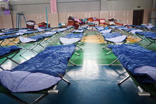 Cots with sleeping bags are placed in the school gym during an emergency