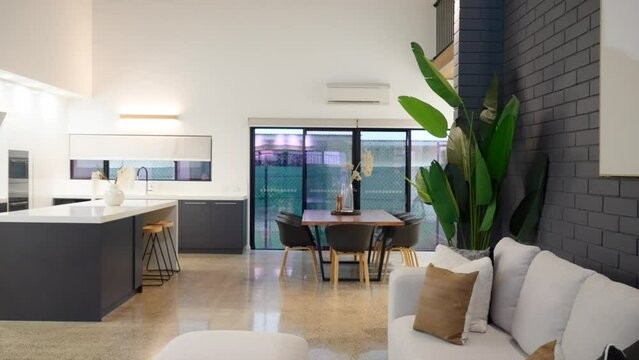 Modern kitchen and dining room with large dining table island bench top, polished concrete flooring and high ceiling luxury home house.