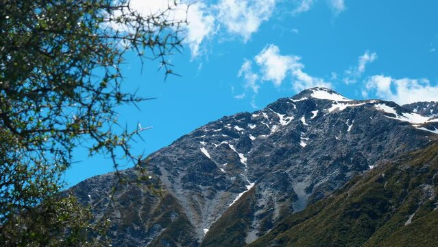 Snow-kissed peaks: Mountain with patches of snow through bushes in captivating stock footage. Nature's wintry beauty revealed.