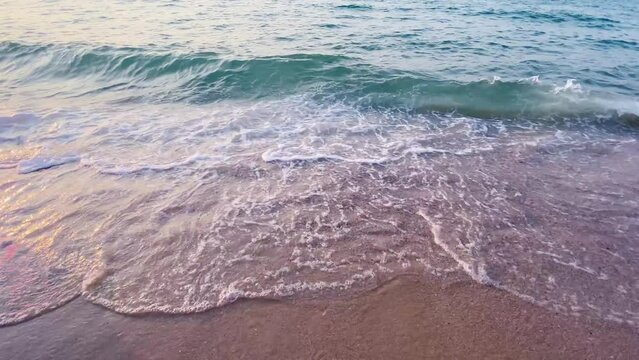 Beach waves gently roll along the sandy shore, beneath a sky painted with clouds, capturing the serene beauty of a summer seascape