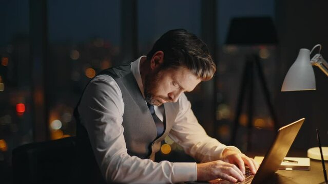 Busy employee working dark office at night. Focused boss typing computer online