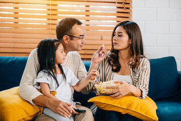 A joyful family enjoys movie time with popcorn in the living room. The father mother son daughter...