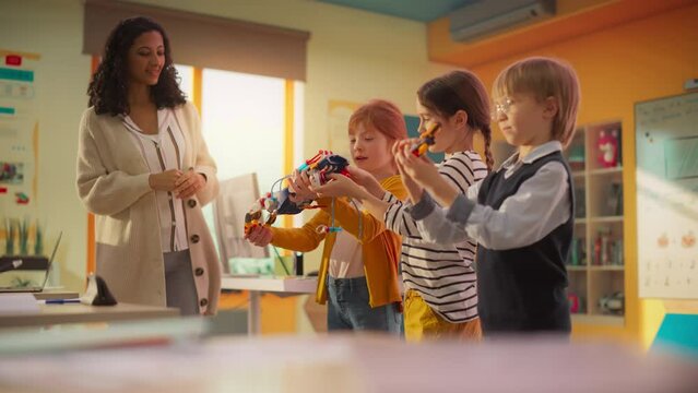 Portrait of Diverse Elementary School Kids Presenting a Robot Hand Project in Front of Class and a Female Teacher. Young Talented Boys and Girls Showing Homework During a Science Class