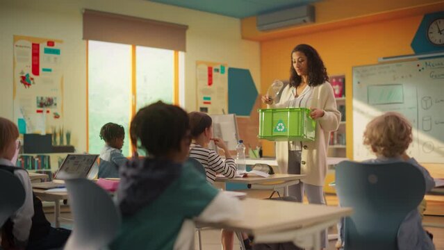 Elementary School Classroom: Enthusiastic Female Teacher Holding an Empty Plastic Bottle and a Box with a Recycling Label and Explaining Ecology and Sustainability Concepts to School Kids