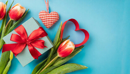 Capture the essence of Mother's Day or Valentine's Day with this lovely image of a giftbox, ribbon bouquet of tulips, and a heart on a blue background.