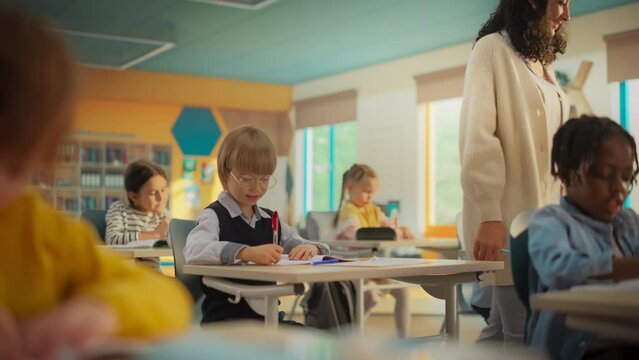 Primary School Children Getting Modern Education and Learning New Skills: Teacher Passing Between Desks, Helping Smart Diverse Kids with Classwork. Schoolchildren Resolving Assignments in Textbooks