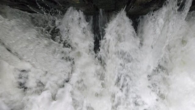 The raging waters of the river Alne in Warwickshire, England as it passes through sluice gates that control the amount of flood water after torrential rainfall.