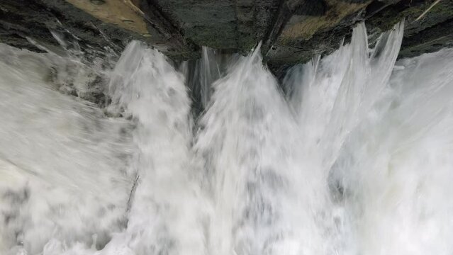 The raging waters of the river Alne in Warwickshire, England as it passes through sluice gates that control the amount of flood water after torrential rainfall.