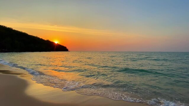 Beautiful Evening Seascape with Waves and Sun Setting over the Beach, Creating a Stunning Reflection on the Water, Surrounded by Clouds and a Tranquil Summer Sky