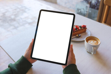 Mockup image of a woman holding digital tablet with blank white desktop screen in cafe