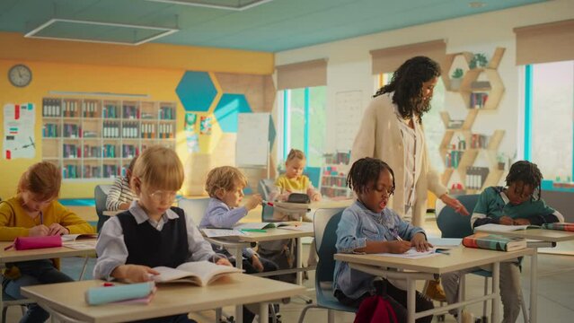 Primary School Children Getting Modern Education and Learning New Skills: Teacher Passing Between Desks, Helping Smart Diverse Kids with Classwork. Schoolchildren Resolving Assignments in Textbooks