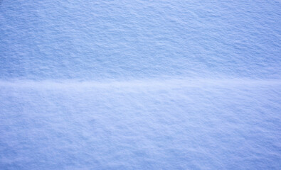 A close-up of a smooth, unbroken expanse of snow, showcasing subtle textures and the gentle play of light and shadow in hues of blue