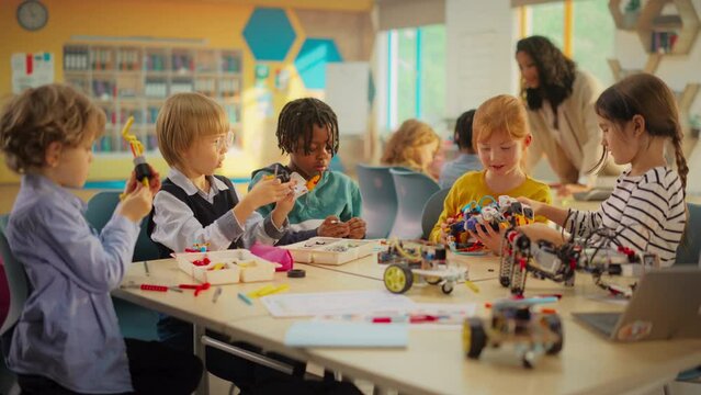 Elementary School Pupils Sitting Behind a Table in a Group, Building a Robot Hand Project for a Science and Technology Fair. Young Boys and Girls Wish to Become Engineers in Robotics