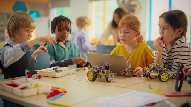 Diverse Primary School Kids Testing an Electric Vehicle with Computer Controls. Girl Using a Laptop to Power the Project in Class. Young Engineering Team Create an Innovative Invention