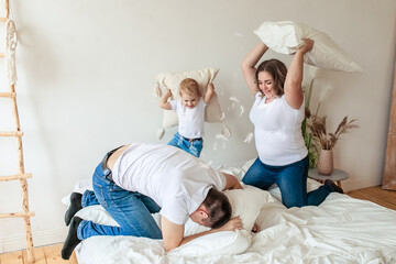 Obraz na płótnie Canvas Happy family fighting pillows in bedroom in the morning