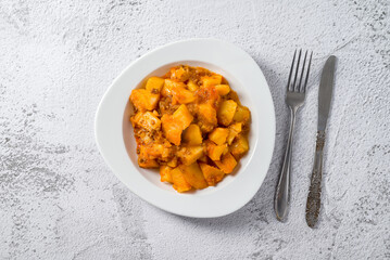 Minced meat and potato dish on white porcelain plate on stone table