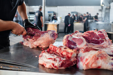 butchering large pieces of fresh meat in close-up. Chef Butcher cutting beef meat with knife on...
