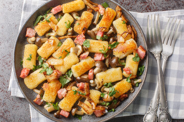 Potato dumpling originating from Poland kopytka served with bacon, onions and mushrooms close-up in...