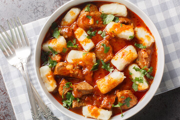 Potato dumplings or kopytka is made with cooked mashed potatoes served meat gravy close-up in a plate on the table. Horizontal top view from above