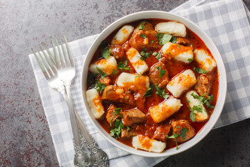 Homemade traditional Polish potato dumplings kopytka served with meat stew close-up in a plate on the table. Horizontal top view from above