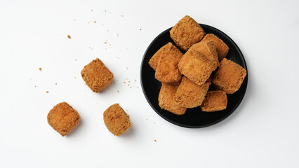 Fried tofu on a black plate in a white background