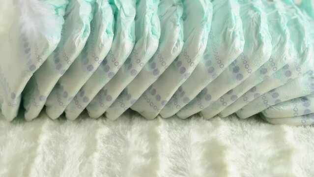 A woman's hand with a feather runs over baby diapers. The concept of comfort and hypoallergenicity for children. Comfort for the skin, close-up