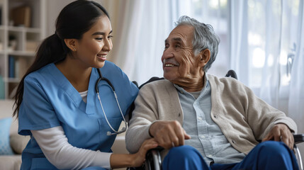 Caring female nurse in blue scrubs smiling and holding hands with an elderly male patient