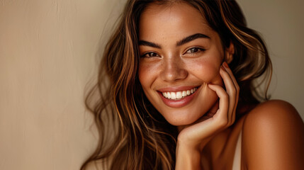 Smiling woman with a hand gently touching her face, displaying clear skin and a joyful expression.