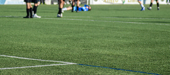 selective focus, view of a soccer field during a match with a player lying on the ground out of focus in the background. sports medicine