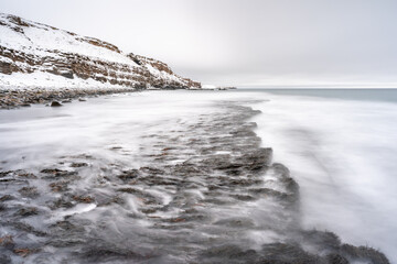 Wintry landscape by the sea in Ekkerøy Norway during the polar night with crashing waves