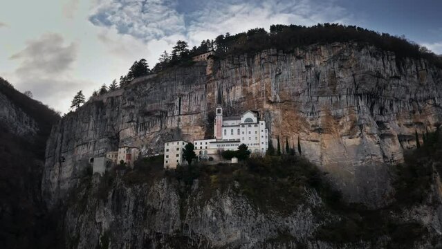 Santuario de la madonna della corona, aerial drone view of a sacred monastery in the mountains of Italy with blue sky and clouds in the background