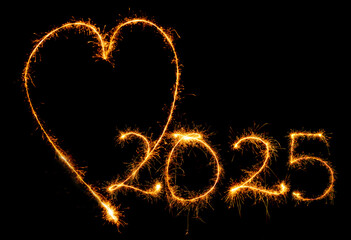 Herz und Jahreszahl 2025 mit Wunderkerze geschrieben vor dunklem Hintergrund.