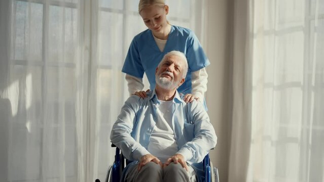 Nurse massaging neck to paralyzed man. Senior male in wheelchair enjoying massage at clinic. Social medical worker provides care support help. Living with legs paralysis, special needs people concept.