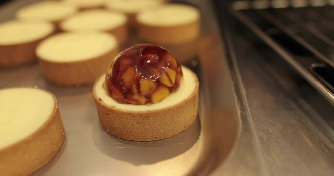 Tartlets on the table of a professional confectioner are decorated with apple-jelly filling.