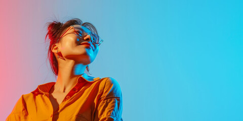 Banner with a confident modern happy young Asian woman on studio blue background and copy space - obrazy, fototapety, plakaty