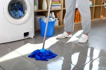 Washing machine leaking and woman mopping the floor