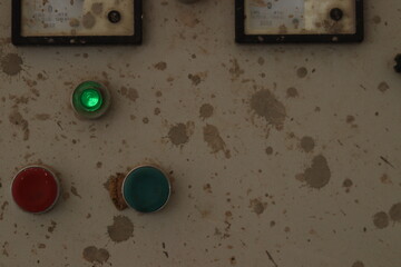 A water tank motor switch button box or panel with paint stains and green indicator light, dirty