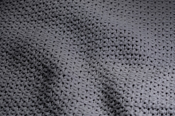 Tło w szarościach,  zbliżenie na strukturę pofałdowanego szarego koca robionego na drutach w zbliżeniu 