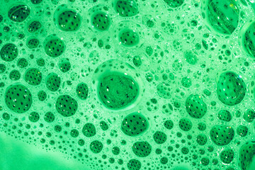 Przezroczyste bąbelki powietrza w pianie na tle zielonej wody, jasne jaskrawe zielone tło 