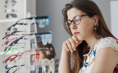Pensive woman choosing her new glasses