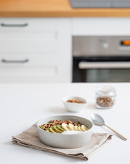 Baked granola with banana and kiwi on the table on a white kitchen background.