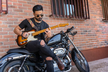 Hipster guitarist playing electric guitar on his motorcycle. Grunge style.