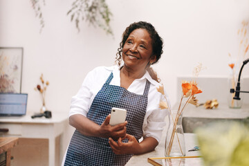 Senior entrepreneur using a smartphone in her small business