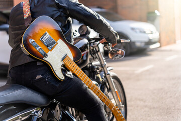 Hipster guitarist with his motorcycle. Rock aesthetic.