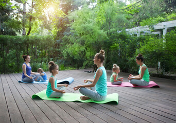 Mothers and daughters doing exercise practicing yoga outdoors