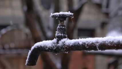 Faucet frozen with ice, snow, frost in winter as a symbol of climate change and extreme weather