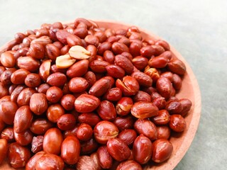 Fried peanuts on wooden plate on gray background. Deep fried peanuts on plate. Half shot. Close up