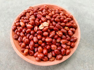 Fried peanuts on wooden plate on gray background. Deep fried peanuts on plate
