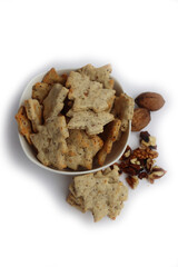 Walnut cookies in shape of a tree in a white bowl with dry walnuts on woooden table 