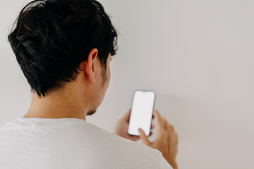 Back view of asian man using mobile phone with white blank screen display, isolated over white background.